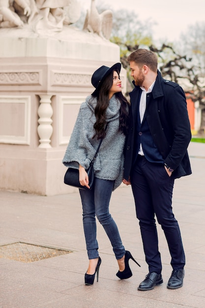 Pareja de moda joven posando en la calle vieja en otoño soleado. Mujer muy hermosa y su guapo novio elegante abrazando en la calle.