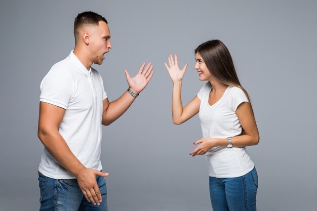 Pareja de moda de pie sobre fondo gris divirtiéndose del trabajo de victoria de buenas noticias en curso