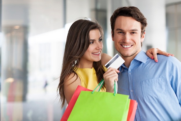 Pareja de moda con tarjeta de crédito y bolsas de compras.