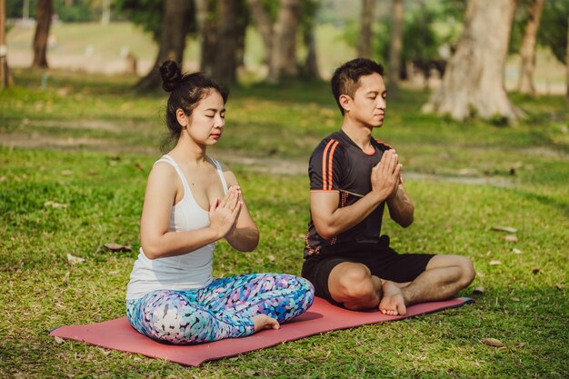 Pareja moderna meditando juntos en la naturaleza