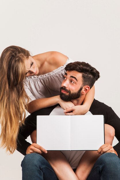 Pareja moderna presentando libro en blanco