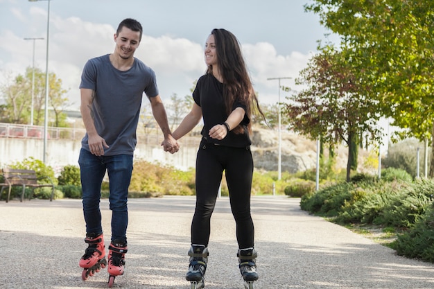 Pareja montando patines y tomados de la mano