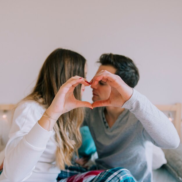 Pareja mostrando el gesto del corazón antes de besar