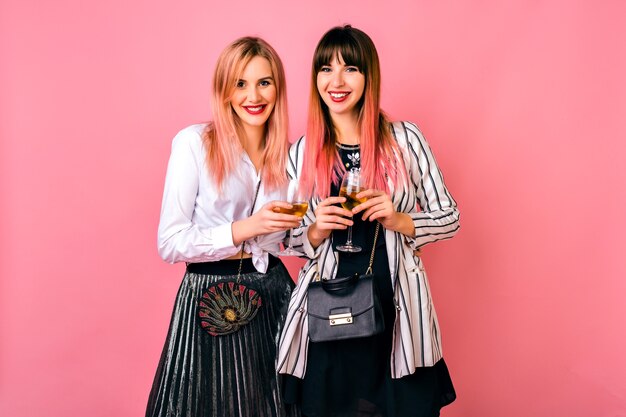 Pareja de mujer hipster de mejor amigo bastante elegante celebrando las vacaciones, elegantes trajes de noche en blanco y negro y peinado rosa de moda, tiempo de diversión juntos.