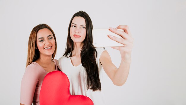 Pareja de mujeres tomando selfie con corazón