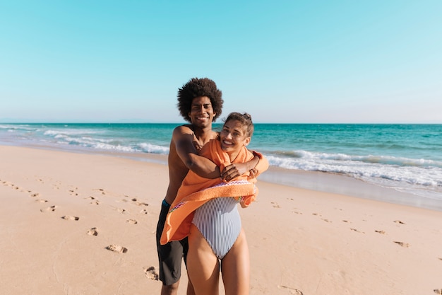 Foto gratuita pareja multicultural abrazando en la playa