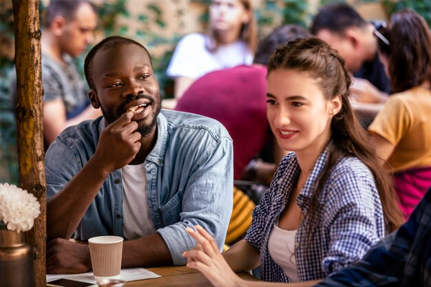 Una pareja multicultural tiene una cita en un acogedor restaurante local en un día cálido y soleado