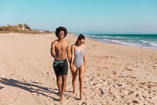 Pareja multiétnica caminando en la playa