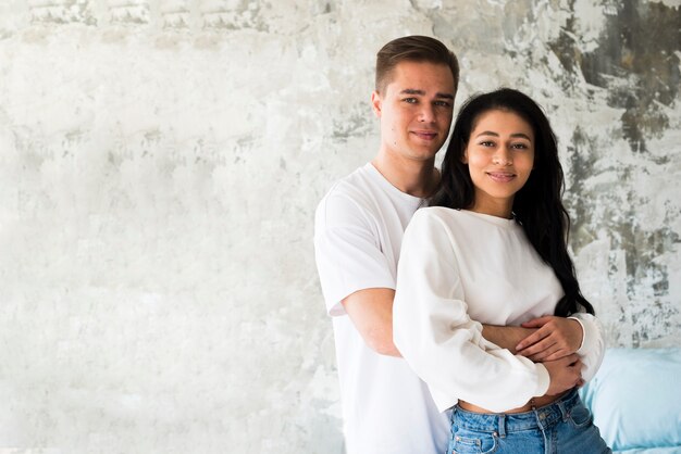 Pareja multirracial abrazando y mirando a cámara