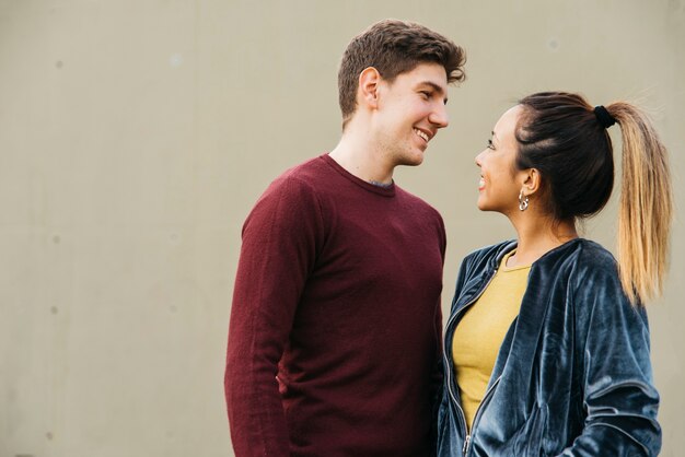 Pareja multirracial abrazando sonriendo y mirando el uno al otro