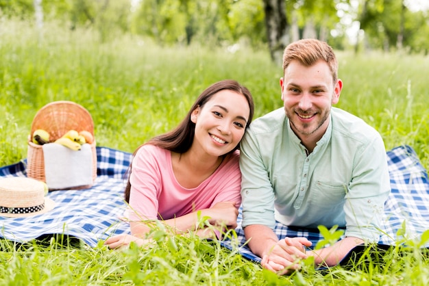 Pareja multirracial sonriente posando en picnic