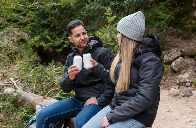 Pareja en la naturaleza bebiendo bebidas