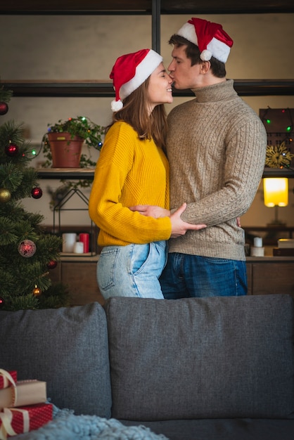 Foto gratuita pareja de navidad con sombreros de santa besos