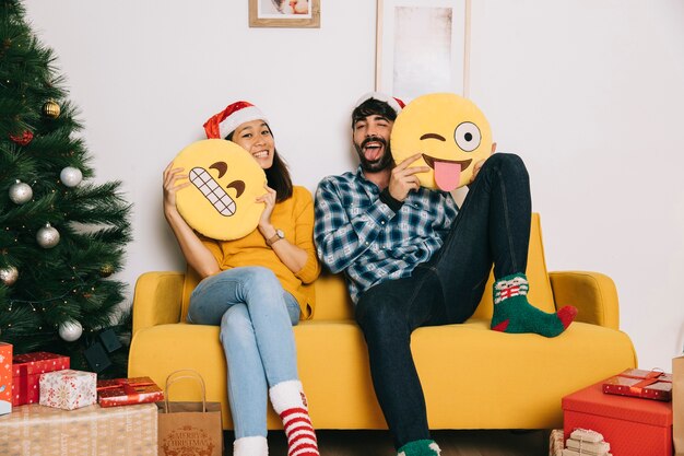 Pareja de navidad sujetando emoticonos