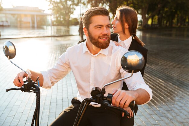 Pareja de negocios despreocupada monta en moto moderna en el parque