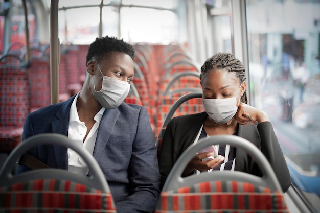 Foto gratuita pareja de negocios con máscara en el autobús mientras viaja en transporte público en la nueva normalidad