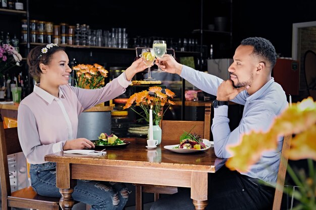 Una pareja negra estadounidense en una cita bebe vino en un restaurante.