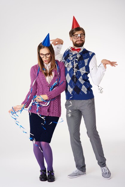 Pareja nerd con cintas y sombreros de fiesta