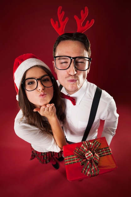 Pareja nerd soplando besos en Navidad