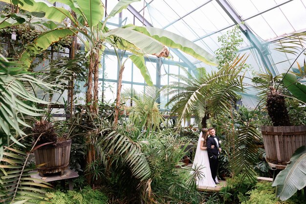 Pareja de novios abrazándose en el jardín con muchas plantas