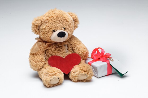 Pareja de osos de peluche con corazón rojo y regalo sobre fondo blanco. Concepto de día de San Valentín.
