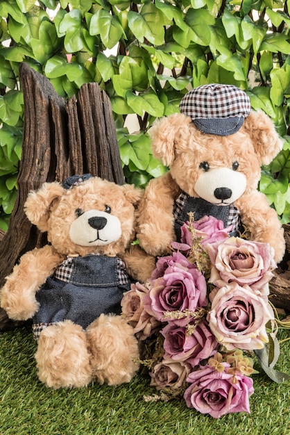 Foto gratuita pareja de osos de peluche con rosas en el jardín