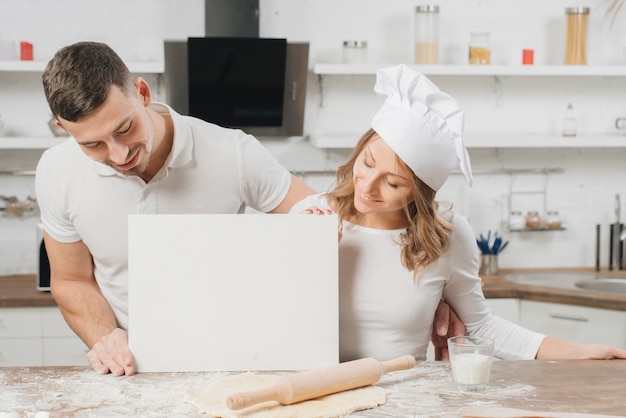 Foto gratuita pareja con papel en blanco en cocina