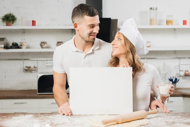 Pareja con papel en blanco en cocina