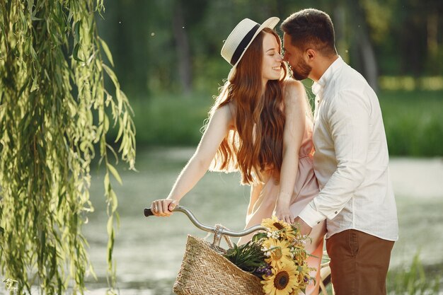 Pareja en un parque de verano. Personas con bicicleta vintage. Chica con sombrero.