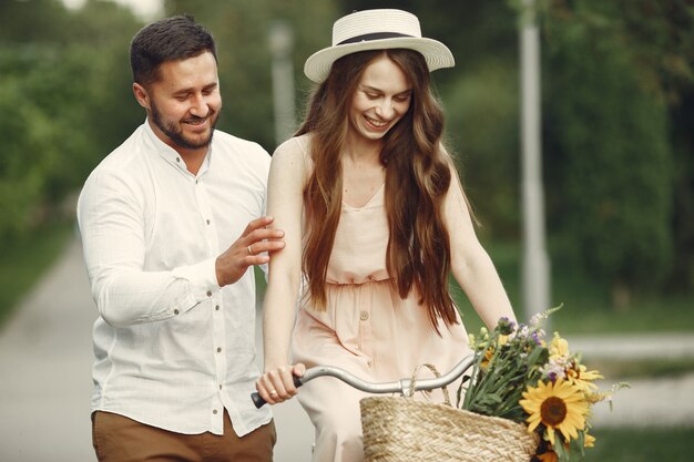 Pareja en un parque de verano. Personas con bicicleta vintage. Chica con sombrero.