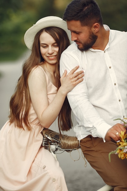 Pareja en un parque de verano. Personas con bicicleta vintage. Chica con sombrero.