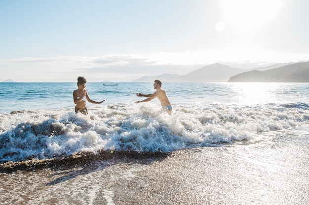 Pareja pasándoselo bien en el agua en la playa