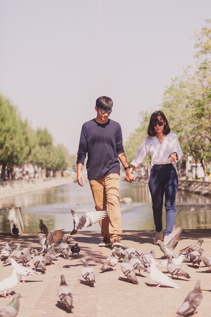 Pareja paseando de la mano por un parque con palomas