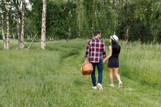 Pareja paseando mientras sostiene cesta de picnic