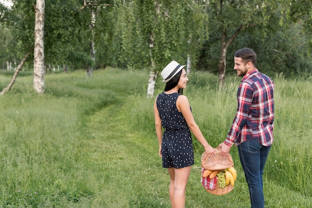 Foto gratuita pareja paseando mientras sostiene cesta de picnic