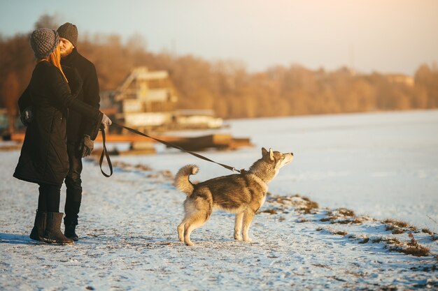 Pareja paseando a su perro mientras se besan