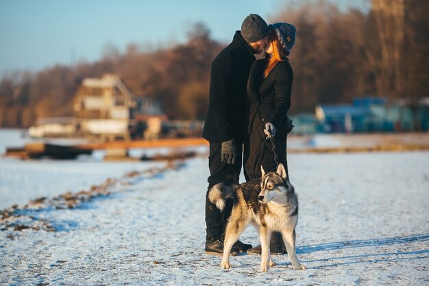 Pareja paseando a su perro mientras se besan