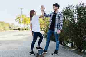 Foto gratuita pareja con patineta dando alta cinco