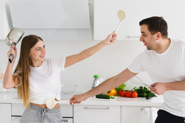 Pareja peleando con utensilios de cocina