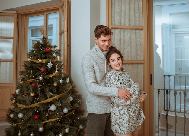 Pareja de pie cerca del árbol de Navidad y abrazos