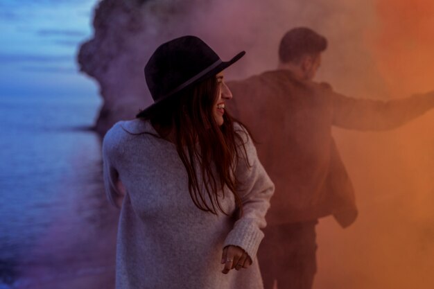 Pareja de pie en el humo en la orilla del mar