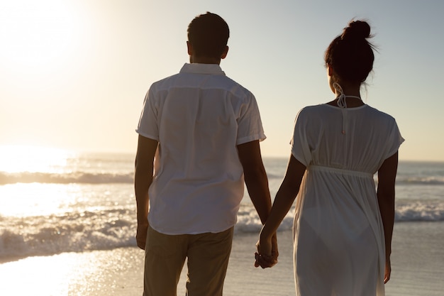 Pareja de pie juntos de la mano en la playa