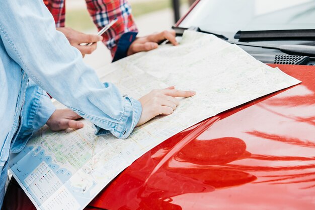 Pareja de pie con el mapa de carreteras en el coche