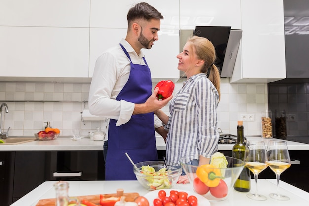 Foto gratuita pareja de pie con pimiento rojo junto a la mesa