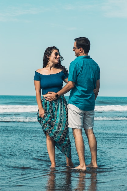 Pareja de pie en la playa en el agua de mar abrazando