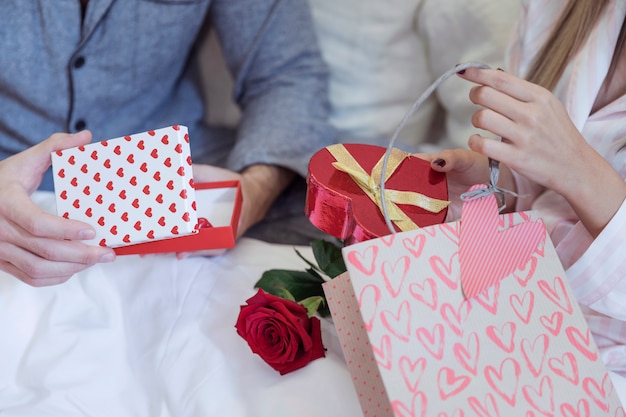 Pareja en pijama sentado en la cama con regalos