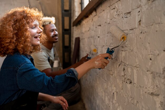 Pareja pintando las paredes de su nuevo hogar juntos