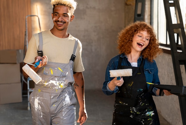 Foto gratuita pareja pintando las paredes de su nuevo hogar juntos