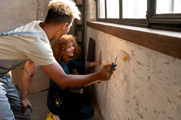 Pareja pintando su nueva casa después de mudarse juntos