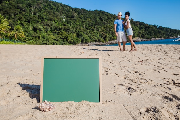 Pareja en la playa con pizarra